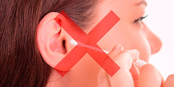 Billedet viser en kvinde, der ved at putte en vatpind i øret. Der er et rødt kryds over billedet.