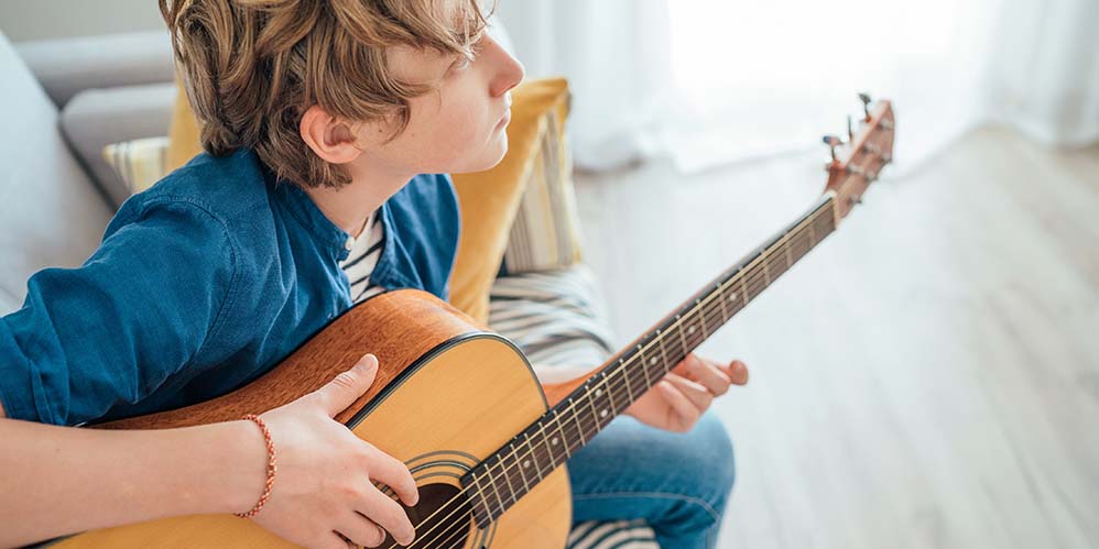 la imagen muestra un chico joven tocando guitarra 