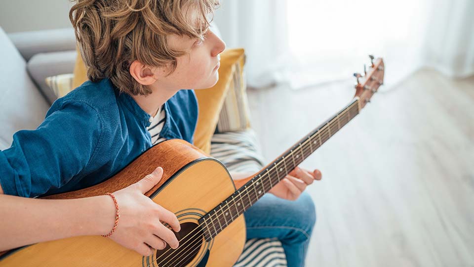 la imagen muestra un adolescente tocando guitarra