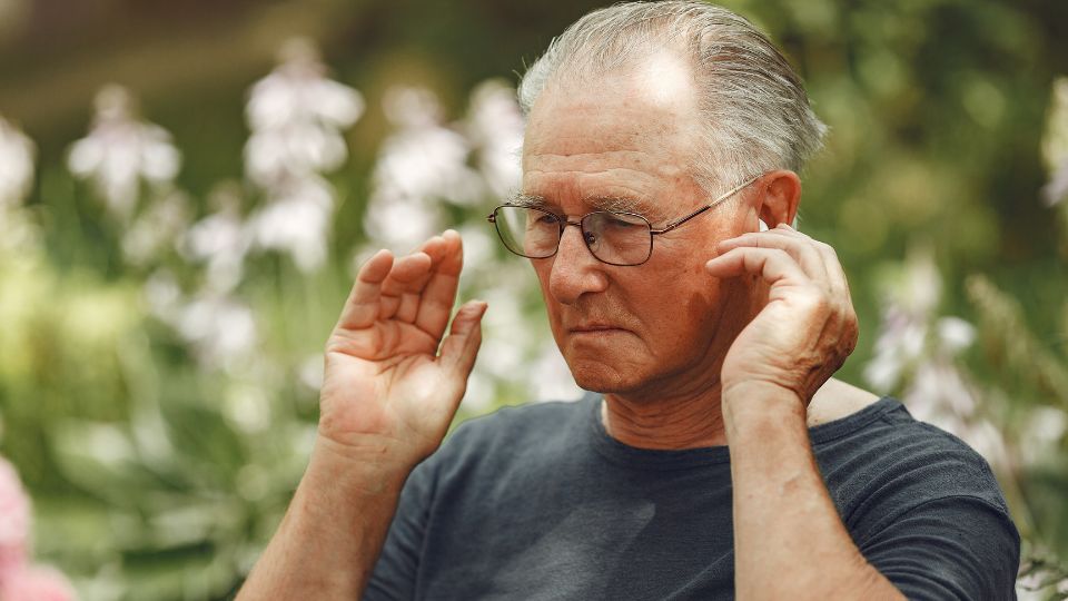 Una persona mayor poniendo su audifono para oir mejor 