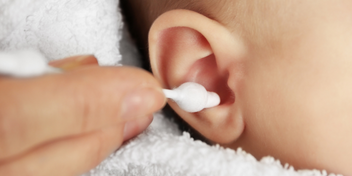 la imagen muestra alguien limpiando el oído de un bebé