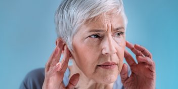 mujer con pérdida auditiva súbita tocando sus oídos