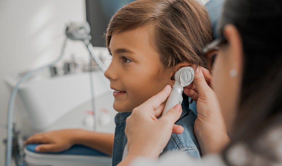 la imagen muestra un audioprotesista examinando el oído de un niño