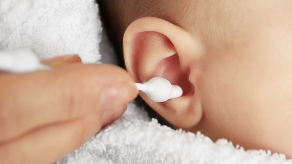 la imagen muestra una persona limpiando el oído de un bebé