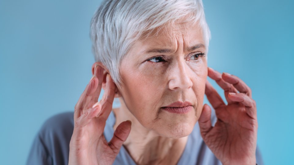 mujer con pérdida auditiva súbita tocando los oídos con las manos