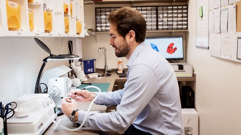 Un audioprothésiste dans le laboratoire LEA en train de manipuler des appareils auditifs