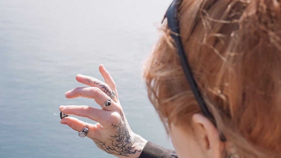Une femme tatouée qui tient des appareils auditifs intra-auriculaires dans sa main en nous les montrant