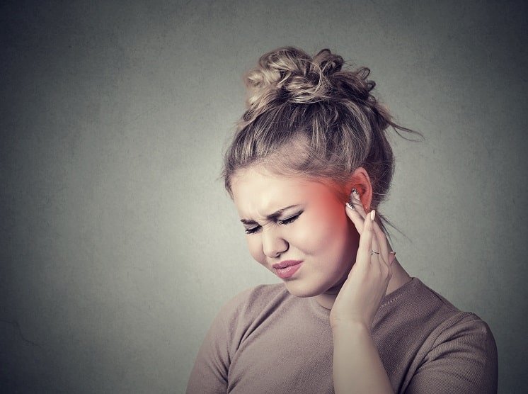 Une femme souffrant d'acouphène se tenant l'oreille de douleur