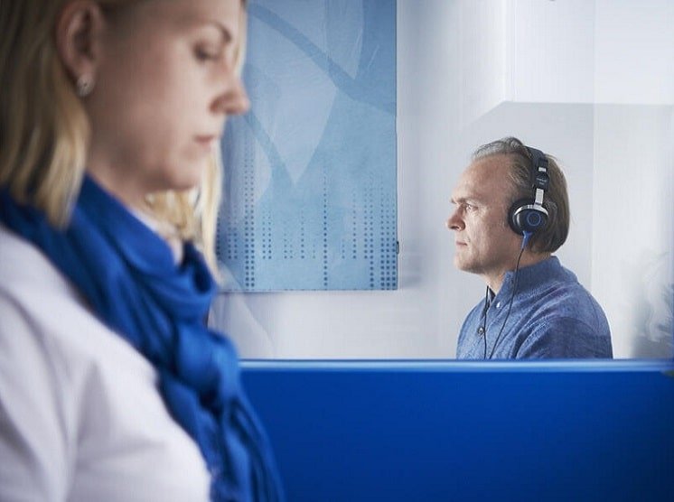 Un homme effectuant un bilan auditif en cabine avec une audioprothésiste