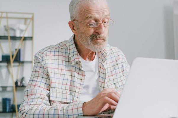 Un senior devant son ordinateur avec ses lunettes