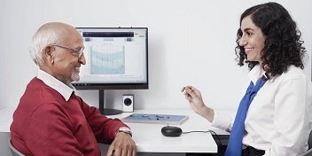 Une audioprothésiste renseigne un patient sur les aides auditives