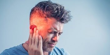 Un homme souffrant d'acouphènes qui se tient l'oreille de douleur