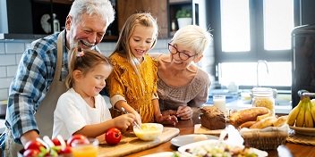 Des seniors appareillés en train  de cuisiner avec leurs petits-enfants