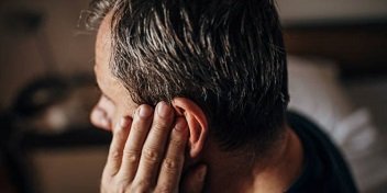 Un homme se tient l'oreille car il souffre d'acouphènes