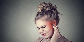 Femme souffrant d'hyperacousie qui se tient l'oreille