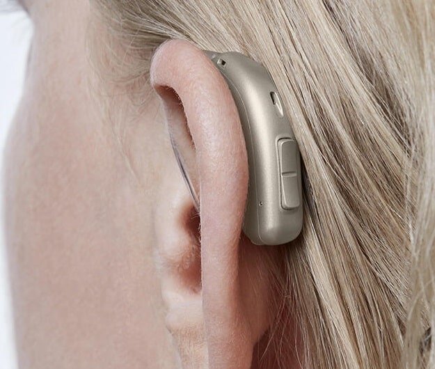 L’image montre une personne portant des appareils auditifs invisibles