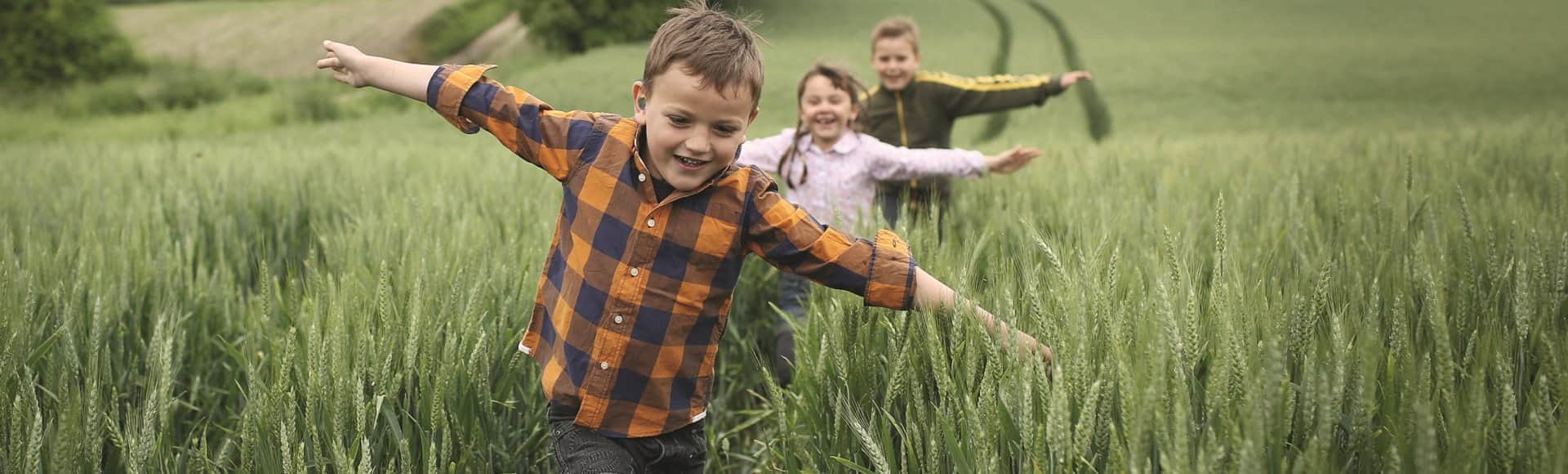Trois enfants avec appareils auditifs jouant dans un champ
