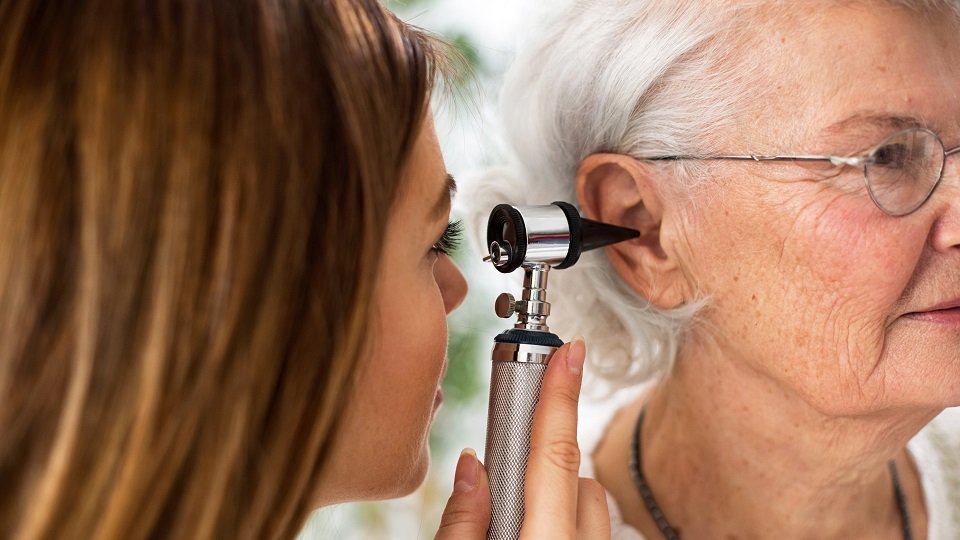 Une audioprothésiste ausculte une patiente pour déterminer si un nettoyage interne des oreilles est nécessaire 