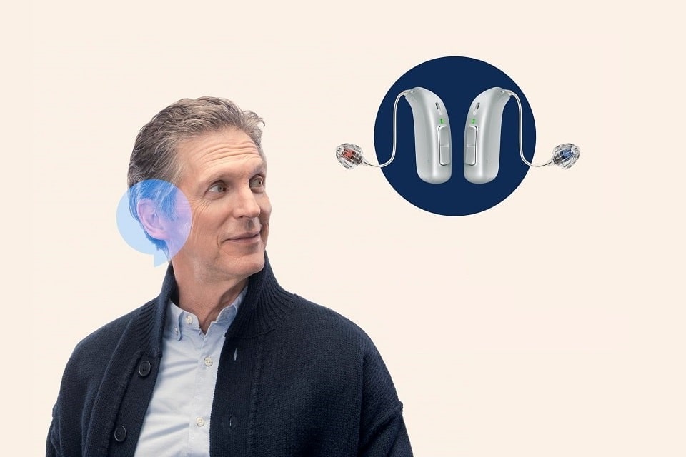 Un homme met un appareil auditif intelligent Audika dans ses oreilles