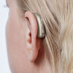 Une femme de profil arrière porte une aide auditive AUDIKAFULL