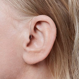 Une femme de profil porte une aide auditive miniRITE