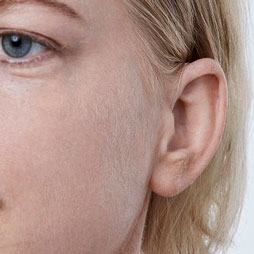 Une femme de face qui porte des appareils auditifs mini-contours
