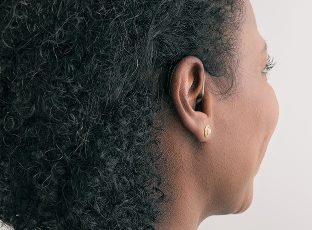 Une femme portant des appareils auditifs mini-contours adaptés à sa couleur de cheveux
