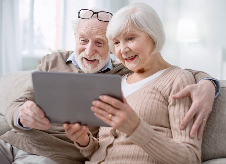 Kobieta i mężczyzna siedzą na kanapie i przeglądają artykuły blogowe dotyczące zdrowia słuchu.