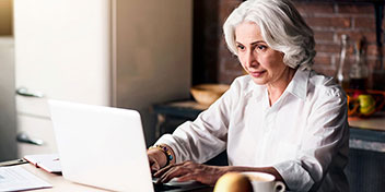 Bild på en kvinna som sitter framför datorn och chattar med Audikas kundservice