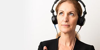 Bild på en kvinna som gör en gratis hörselkoll hos Audika för att få en indikation på hur hon hör