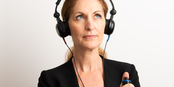 Kvinna med hörlurar som har träffat en audionom i Skåne.