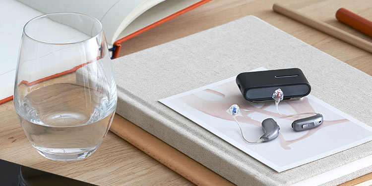 Bild på ett par hörapparater med bluetooth som ligger på ett bord.