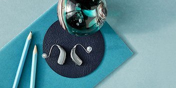 Bild på ett par hörapparater och pennor som har Brainhearing teknik.