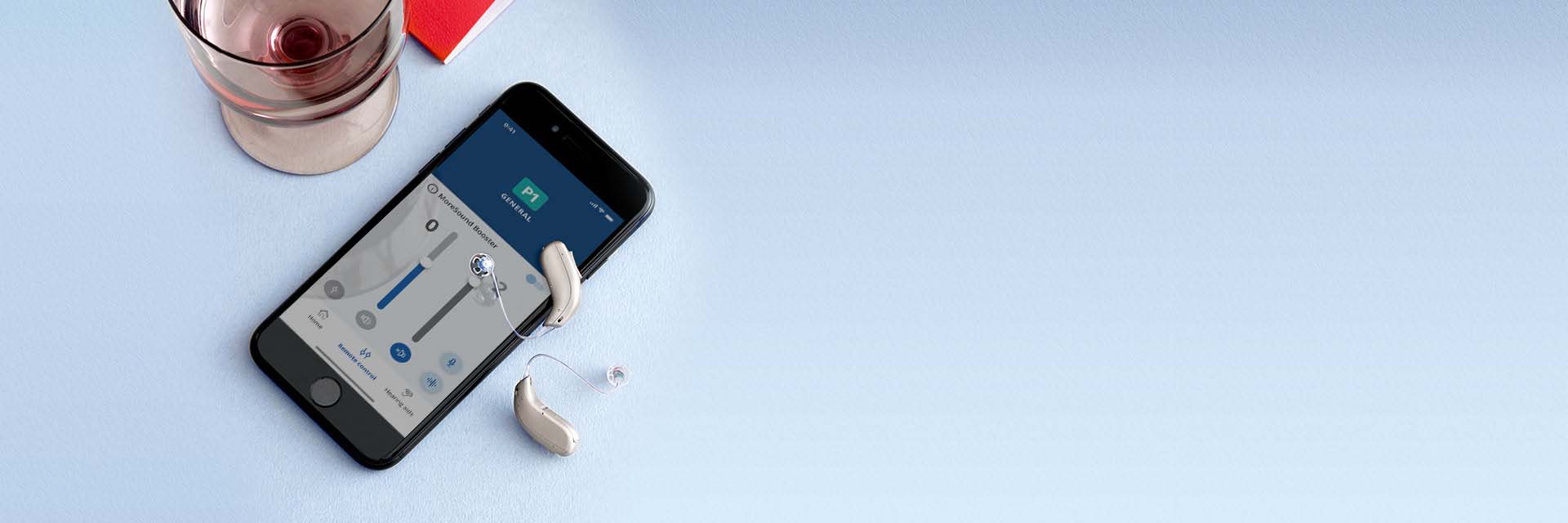 Bild på telefon och två hörapparater som har Bluetooth. Hörapparater är silverfärgade.