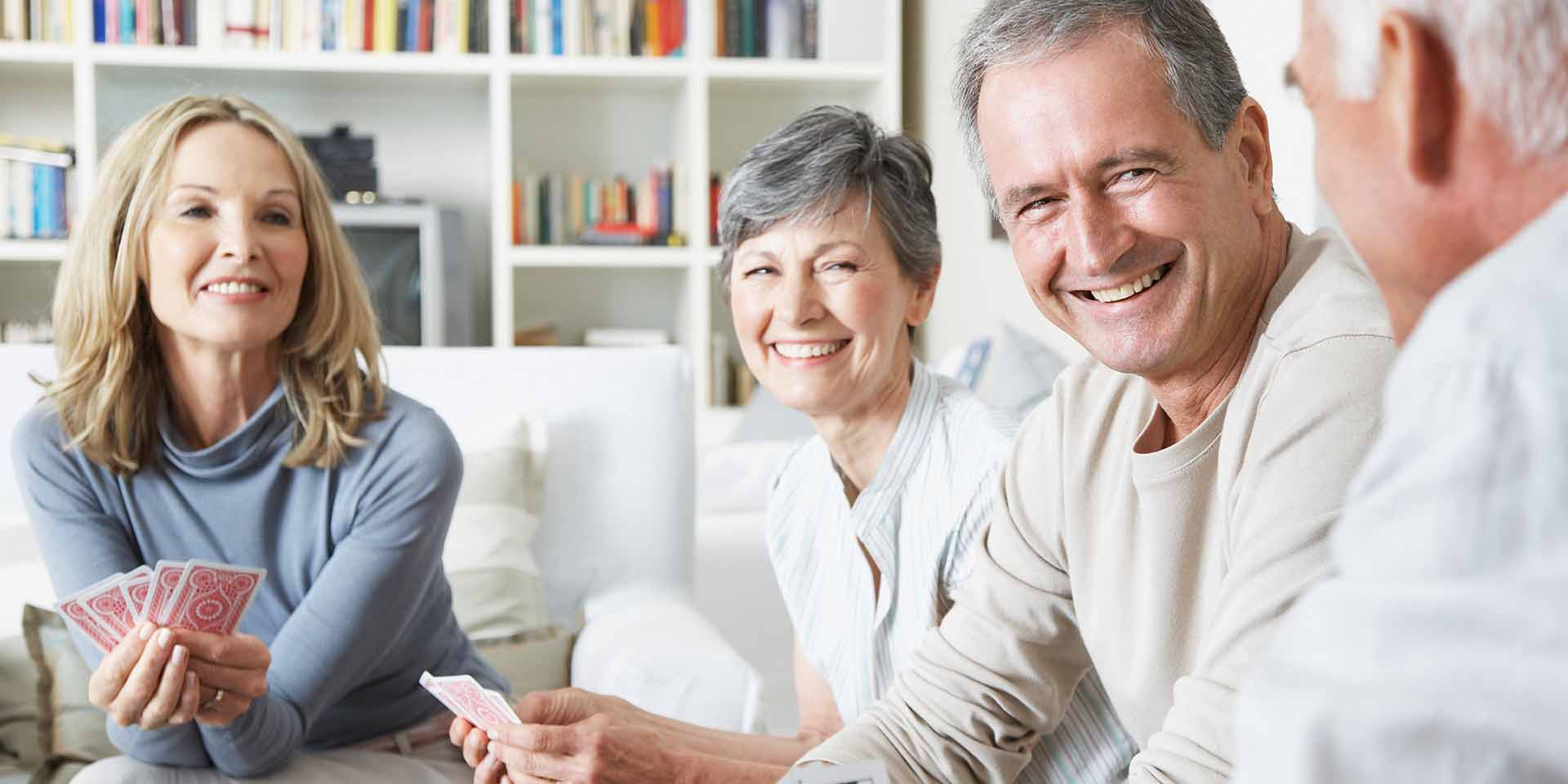 Fyra glada äldre personer som kommunicerar och skrattar. Har hörapparater.