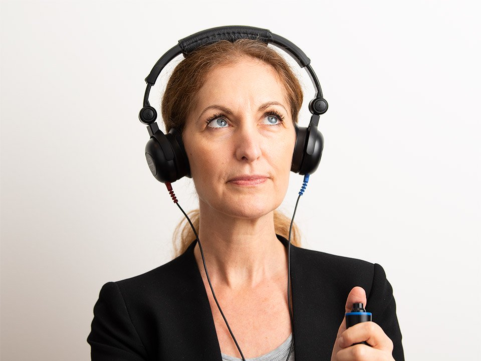 En kvinna som har hörlurar och gör ett hörseltest så du ser att hon testar sin hörsel.