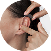 Bild som visar hur man placerar en hörselapparat i örat på en person.