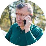 Bild på en man som har svårt att tala i telefon på grund av sin hörselnedsättning och får hjälp av en anhörig