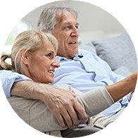 Bild på äldre par som sitter framför TVn och har hörselnedsättning