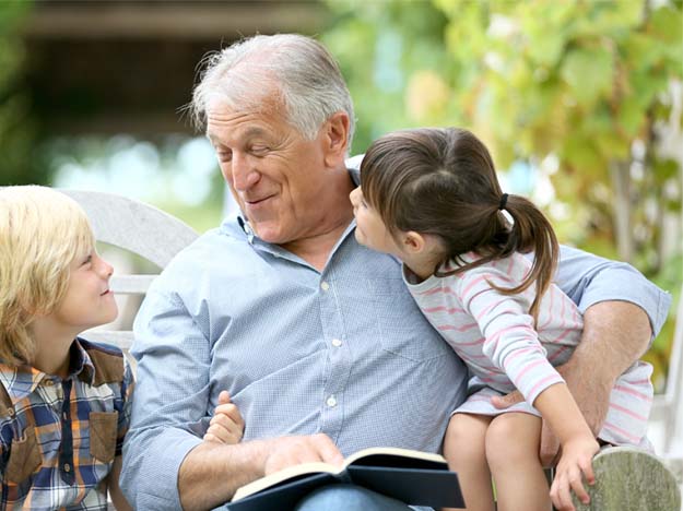 Bild på en man som sitter med sina barnbarn och lyssnar på deras historier
