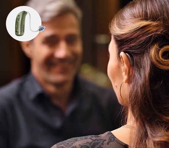 Bild på en man som tittar på en kvinna som har en hörapparat som hon har provat ut hos Audikas experter på hörsel