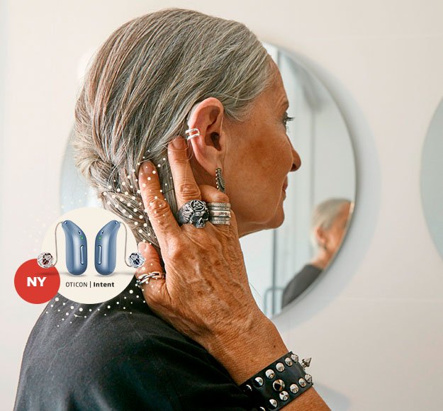 Bild på en kvinna som håller bort sitt hår för att visa sina hörapparat Oticon Intent som ger henne personligt hörselstöd