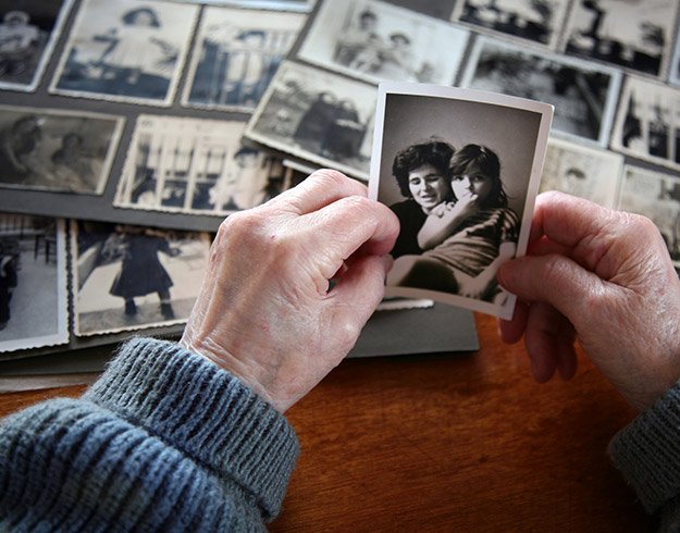 Bild på en person som tittar på gamla bilder som har förlorat minnet på grund av obehandlad hörselnedsättning
