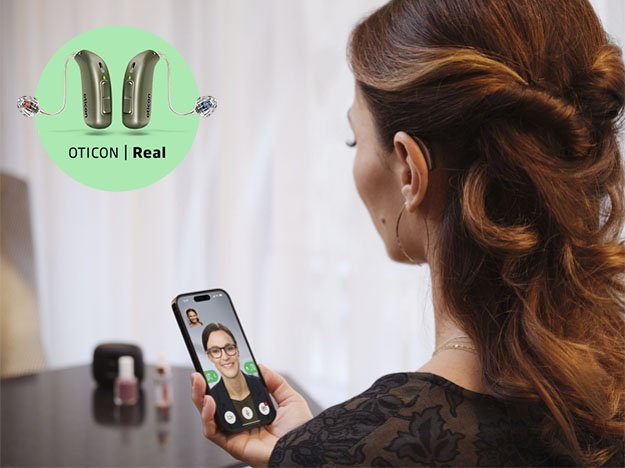 Bild på en kvinna som har en Oticon Real hörapparat som talar i telefon med fokus