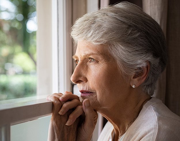 En kvinna som tittar ut från ett fönster som har tecken på nedsatt hörsel och vill åtgärda det