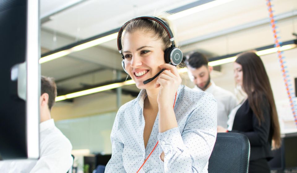 Call center agent using a headset and smiling happily while on a call with a client