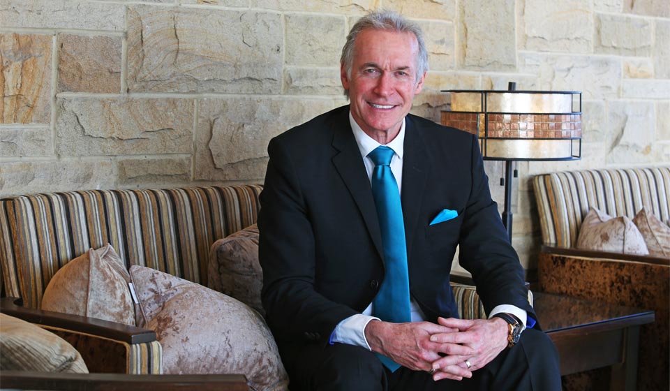 Image shows Dr. Hilary Jones sitting on a chair smiling