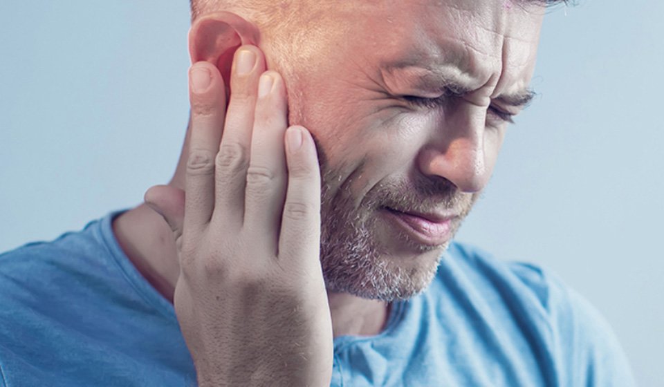 Image shows a man with tinnitus and he wonders if there is a cure for tinnitus