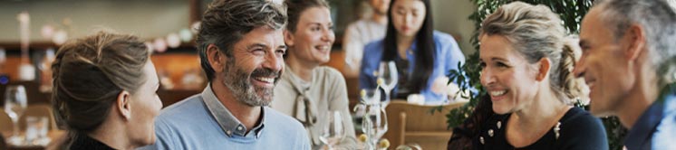 Image shows a man wearing hearing aids and socialising happily at a restaurant