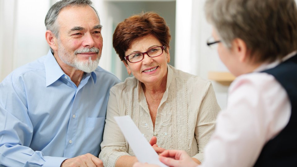 Image shows elderly couple talking to an audiologist